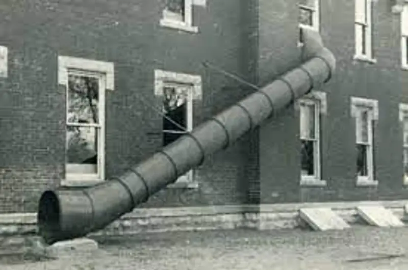 A spiral metal fire-escape chute running from an upper window down the side of an old brick building