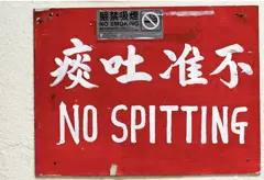 Red NO SPITTING sign in Chinese and English